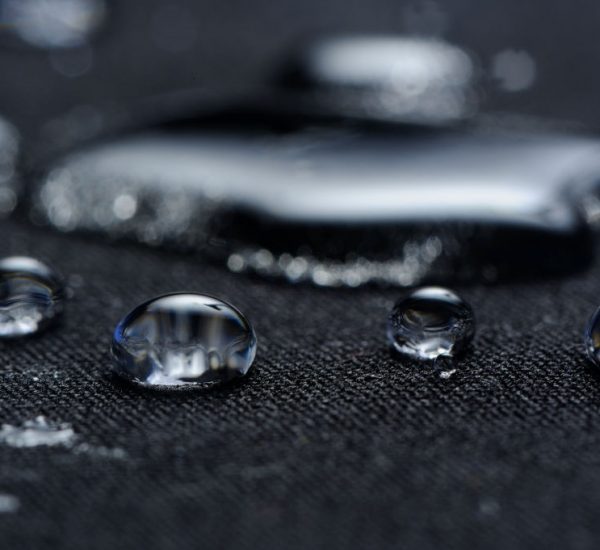 Macro of water drops on black waterproof fabric